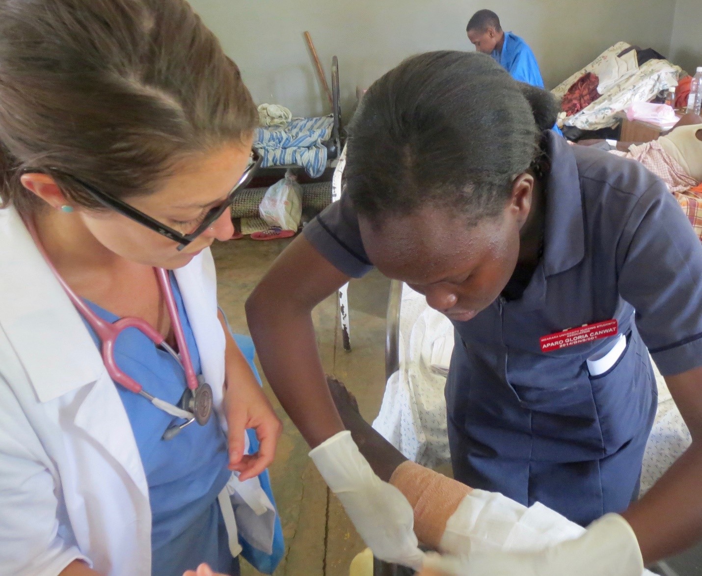 Nursing Fellow Sophia Harden supervises a student at Mbarara Regional Referral Hospital while attending to the dressing of a patient with a burn injury (2016)